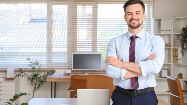 Bookkeeping workspace with an open ledger, calculator, laptop displaying financial charts, receipts, and coins on a desk, illustrating organised financial record-keeping.