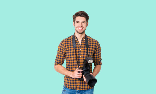 Man standing holding a DSLR camera for basic photography course