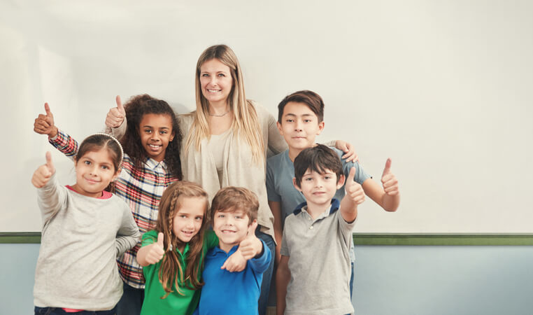 Multicultural group of children holds thumbs up with a childminder