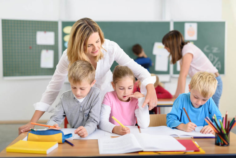 Two teachers assisting students in a classroom