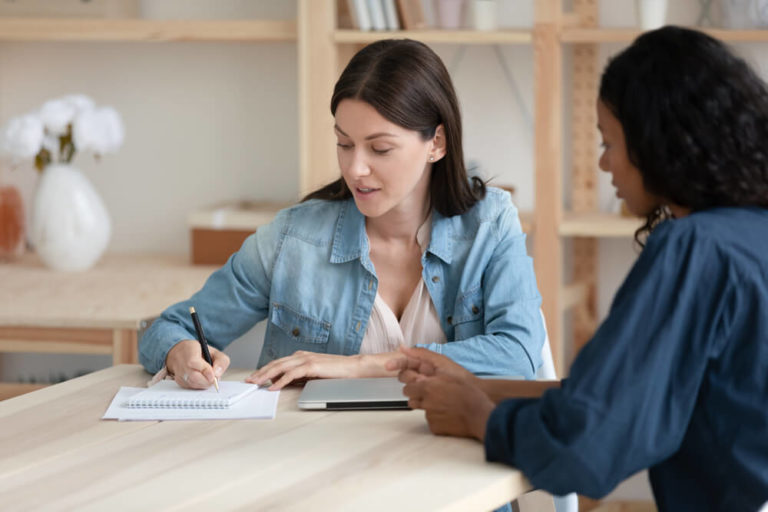 One woman helping other one to write her resume