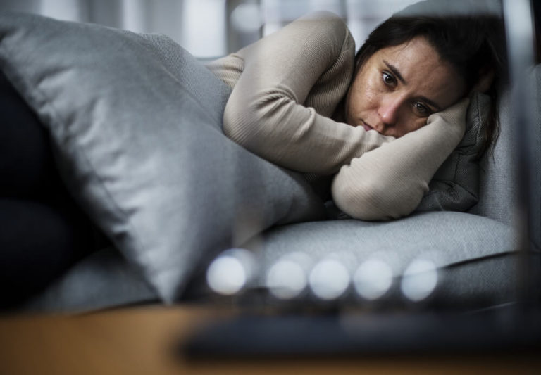 Depressed woman laying in sofa