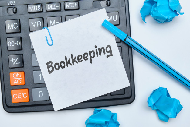 Bookkeeping written on sticky note above a calculator