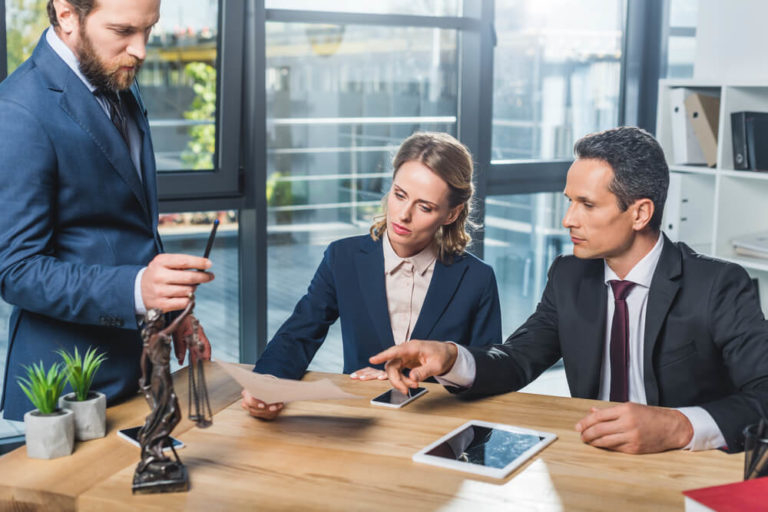 Group of paralegals in suits discussing contract together in office