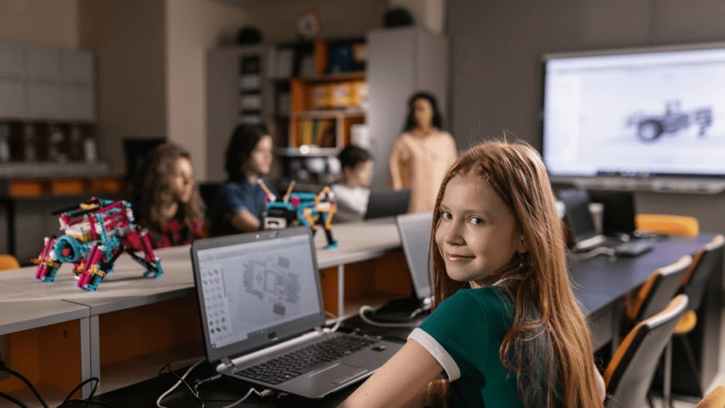 a child lookin at the camera and laptop in front for What is e-safety