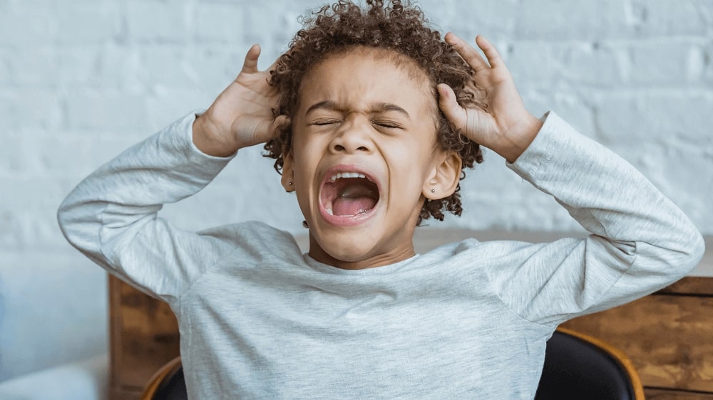 A child is screaming loudly, displaying attention-seeking behavior.