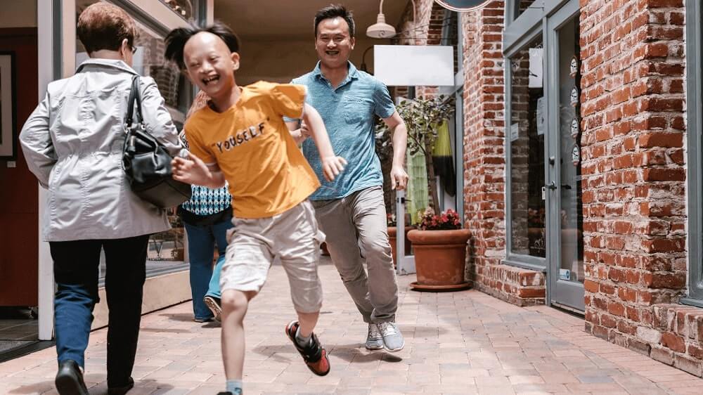 A happy boy and his father joyfully running together in the streets, showcasing sensory seeking behaviors.