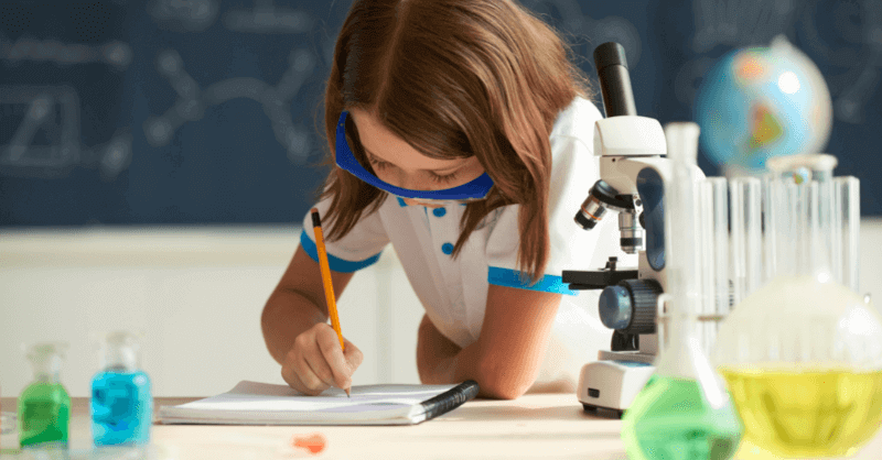 A girl in a school setting is writing answers for a science test.