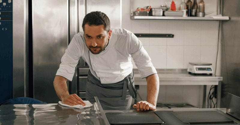 A person wiping a spill off a kitchen table.