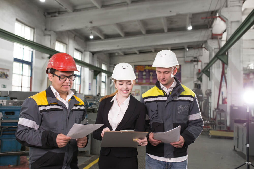 Three construction workers discussing a project while holding a plan.