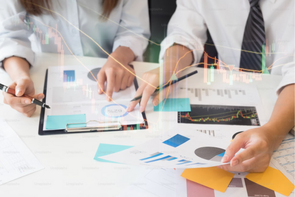 “Business analytics team analyzing financial charts and graphs with magnifying glass, indicating detailed market research and data analysis.”