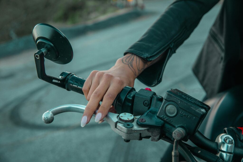 Detailed close-up of a hand gripping a motorcycle handlebar outdoors.