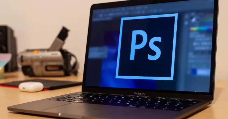 Basic Photoshop setup showing a laptop screen with editing software open and camera equipment nearby for creative work