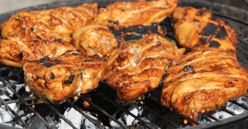 Properly reheated chicken on a grill, ensuring food safety by reaching 165°F to prevent food poisoning