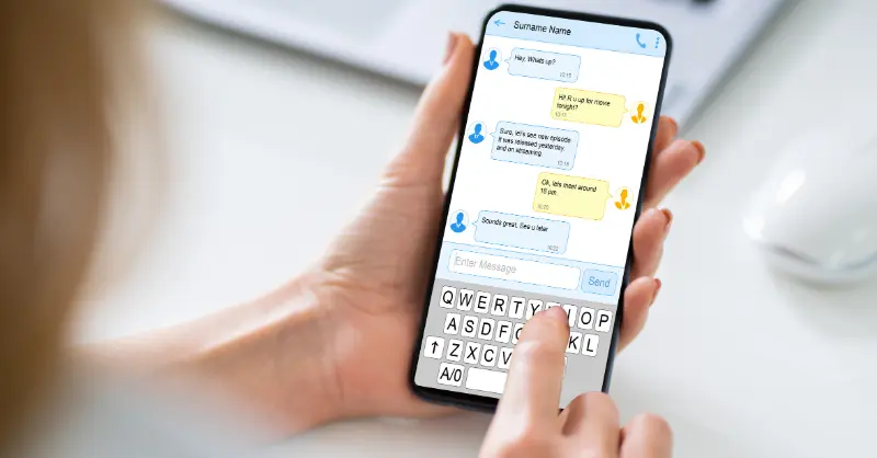 Texting via instant messaging app with friendly exchange and time-stamped replies shown on smartphone display