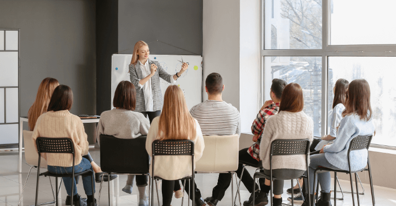 Sales Enablement Training Specialist leading a workshop with professionals in a modern office, enhancing team skills through structured learning