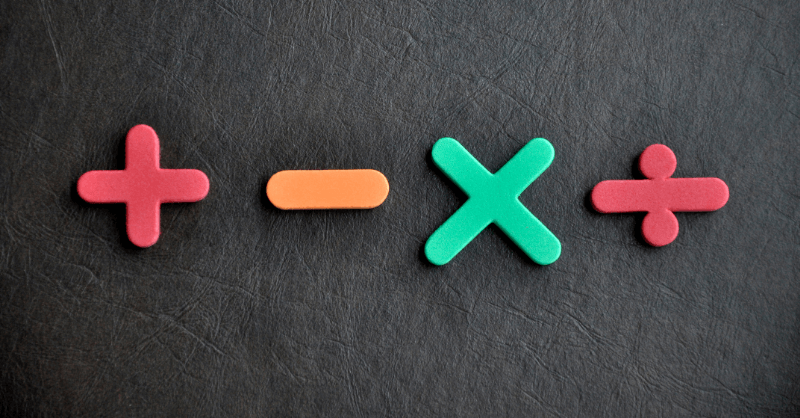 Colorful foam symbols for addition, subtraction, multiplication, and division on a dark background, representing key operations in the BODMAS rule.